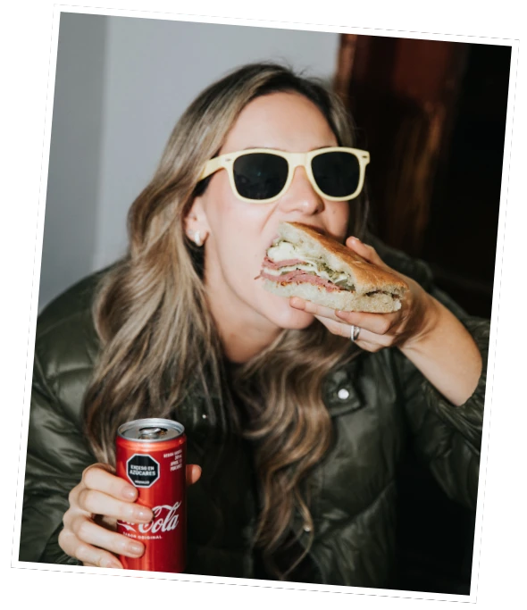 Cliente disfrutando un sándwich artesanal del menú con bebida | Bros and Subs